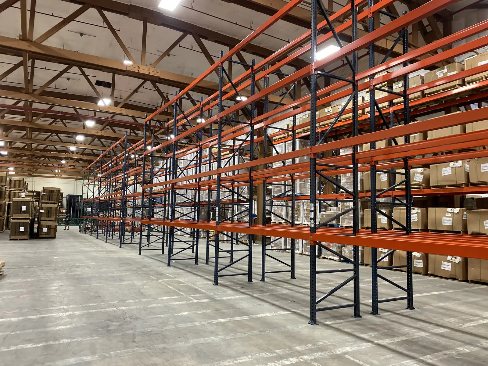 Installed orange and navy pallet racking in a working warehouse