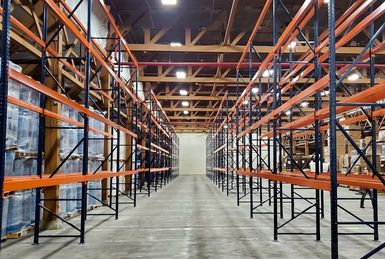 Long aisle of orange and navy pallet racking in a warehouse